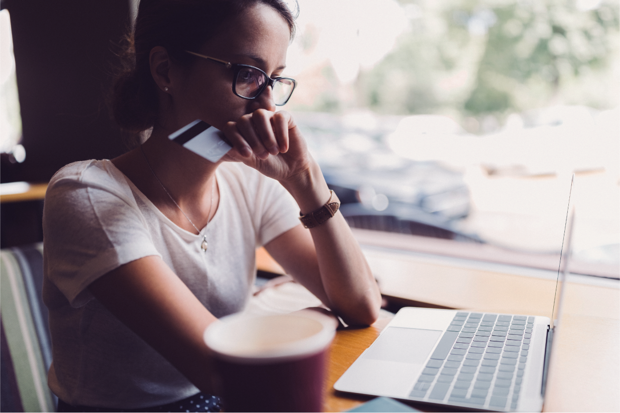 Woman using a laptop and holding a credit card - friendly fraud - Shift4