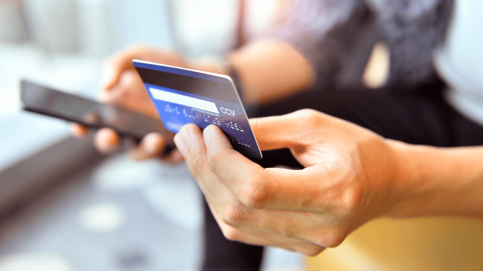 Man holding a smartphone and credit card representing an online chargeback - Shift4